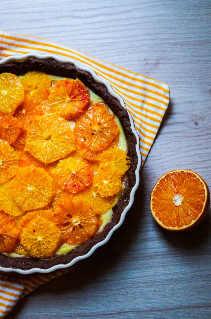 Blutorangen-Tarte auf gestreiftem Tuch mit Blutorange daneben