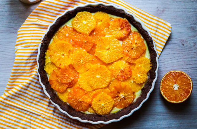 Blutorangen-Tarte auf gesteriftem Tuch und Blutorange daneben